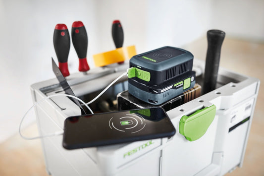 Festool PHC 18 Handy Ladestation mit 18V Akkupack, USB-A, USB-C und induktiver Ladefläche, Zubehör im Hintergrund