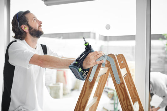 Festool CXS 18-Basic Akku-Bohrschrauber bei Anwendung an Holzleiter, ergonomische C-Form Griff