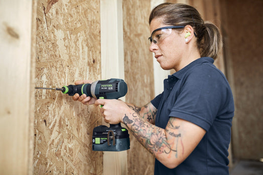 Festool TPC 18/4 Akku-Schlagbohrschrauber in Anwendung beim Bohren in Holzwerkstoff mit Schutzbrille und Akku