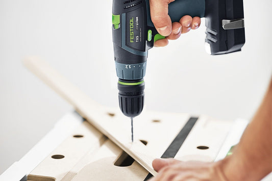 Festool TXS Akku-Bohrschrauber mit Schnellspannbohrfutter beim Bohren in Holzwerkstück mit Lochschablone.