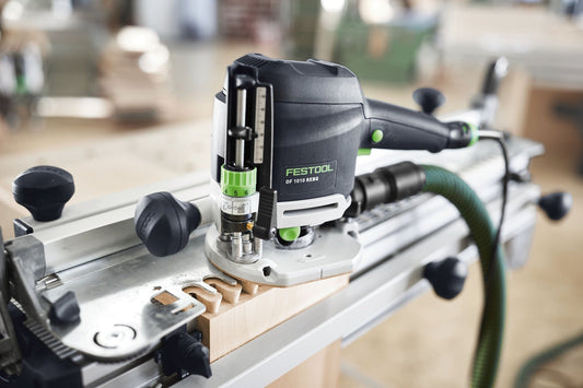 Festool OF 1010 REBQ Oberfräse mit Führungsschiene auf Arbeitstisch, LED-Beleuchtung und Fräswerkzeugen sichtbar