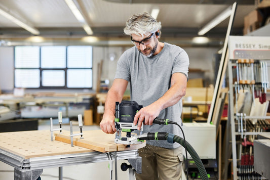 Festool Oberfräse OF 1400 EBQ-Plus mit Absauganlage beim Fräsen in Holzwerkstück mit Anschlagschiene