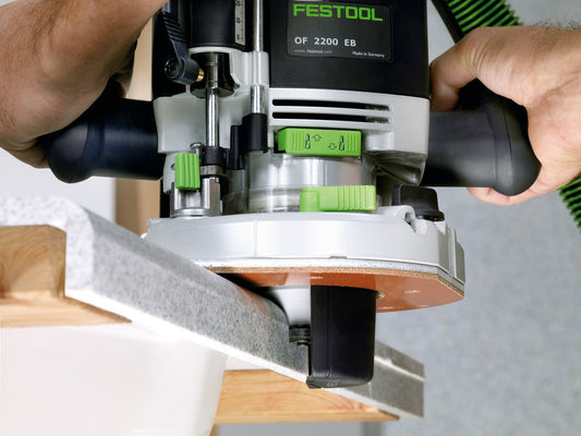 Festool OF 2200 EB Oberfräse mit Laufsohle beim Fräsen an Holzkante, Hände halten Maschine.