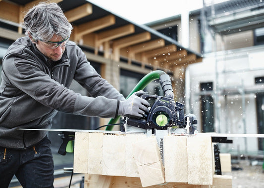 Festool Schwertsäge SSU 200 EB-Plus beim Sägen von Holzbrettern mit Absaugschlauch und Führungsnut
