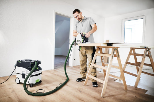 Festool CTM MIDI I Absaugmobil in Anwendung beim Sägen von Holzplatten auf Arbeitstisch mit Absaugschlauch