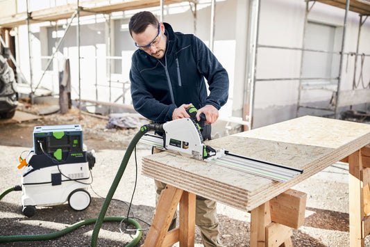 Festool CTM 26 EI Absaugmobil im Einsatz beim Sägen von Sperrholz auf einer Baustelle mit Absaugschlauch