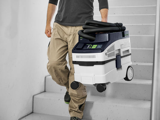 Festool CLEANTEC CT 15 Absaugmobil auf Baustelle, Mann trägt kompakten Staubsauger die Treppe hinauf