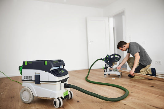Festool CLEANTEC CTM 26 EI-FLR Absaugmobil im Einsatz beim Schleifen auf Holzboden mit Schleifer und grünem Saugschlauch