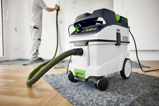 Festool CLEANTEC CTM 36 EI AC Absaugmobil mit AUTOCLEAN-Filter bei Anwendung auf Baustelle, grüner Saugschlauch angeschlossen