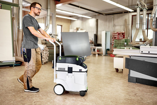 Festool CTM 48 EI Absaugmobil in Werkstatt, Mann bedient Handgriff, weiß-schwarzes Gerät mit grünen Griffen