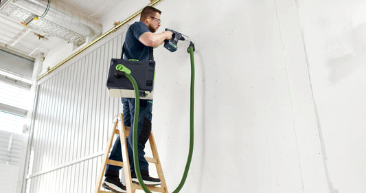 Festool CTLC SYS I-Basic Akku-Absaugmobil im Einsatz auf Leiter mit grünem Saugschlauch an Wand