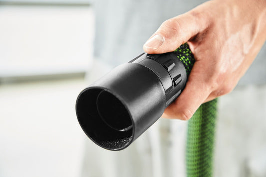 Festool Absaugadapter D 50/D 36 in Hand mit grünem Saugschlauch, offene Adapter-Öffnung sichtbar