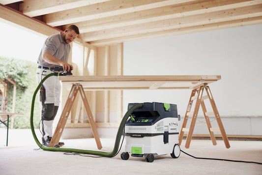 Festool CLEANTEC CTM MIDI I AC Absaugmobil mit Schleifer im Einsatz auf Baustelle, grüner Absaugschlauch angeschlossen.
