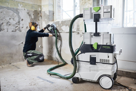 Festool CLEANTEC CTM 36 EI Absauganlage bei Sanierungsarbeiten, Arbeiter mit Schleifer an Wand, Absaugmobil mit Schlauch im