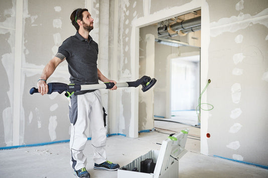 Festool PLANEX LHS 2 225 EQI Langhalsschleifer bei Deckenarbeiten mit LED-Lichtring auf Baustelle.