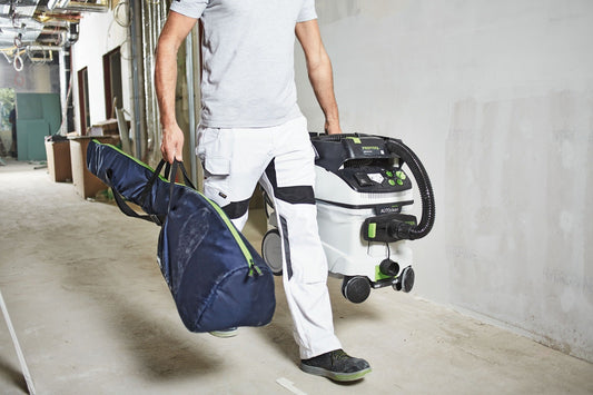 Festool PLANEX Transporttasche mit Schulterriemen beim Transport neben Absauganlage auf Baustelle