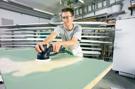Festool Exzenterschleifer beim Schleifen einer Gipskartonplatte in der Werkstatt mit Schleifteller