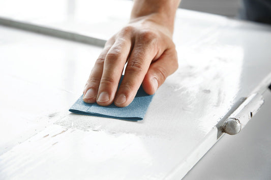 Festool Handschleifpapier Granat in Anwendung beim manuellen Schleifen einer weißen Oberfläche