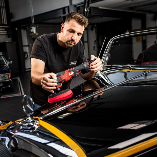 Mann poliert Fahrzeugoberfläche mit FLEX Akku-Poliermaschine PE 150 18-EC C – professionelle Autopflege mit kabellosem Polierer in hochwertiger Werkstattumgebung.