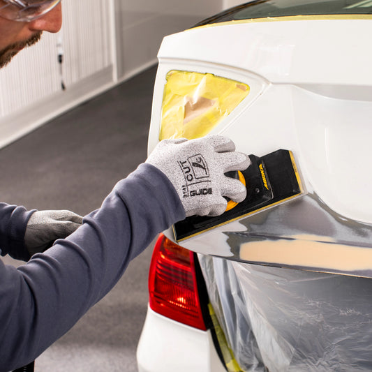 Anwendung von Mirka Iridium Schleifpapier auf Autokarosserie – präzises Handschleifen mit Schleifklotz zur Oberflächenvorbereitung bei Lackierarbeiten.